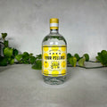 Four Pillars gin bottle with yellow label on a gray surface with green leaves in the background