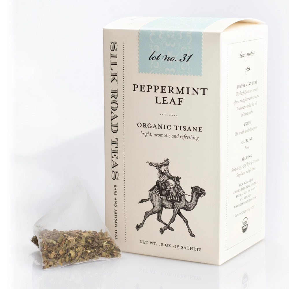 Silk Road Teas Peppermint Leaf Organic Tisane tea box in cream packaging with a small clear bag of loose tea leaves in front, on a white background.