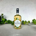 Bottle of Walcher Elderflower liqueur on a light surface with greenery in the background